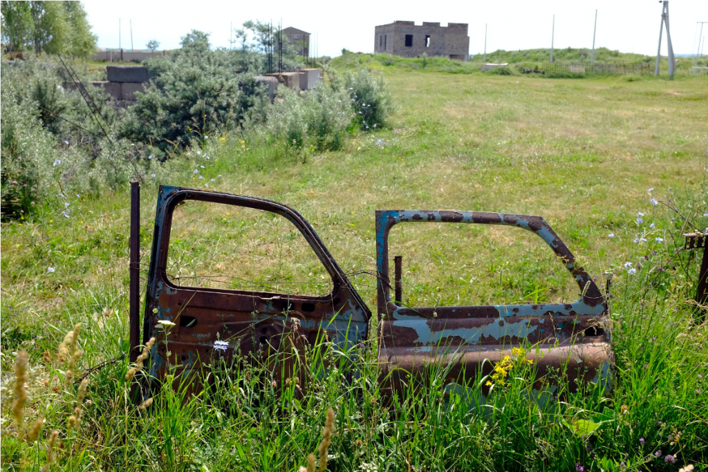 Rusty car doors balanced in a grass field